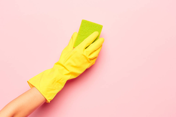 The womans hand cleaning on a pink background. Cleaning or housekeeping concept - Φωτογραφία, εικόνα