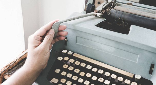 Man's Asian hand typing vintage retro typewriter machine work writer on office desk. - Photo, Image