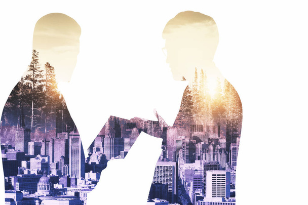 Young businessmen silhouettes discussing contract on abstract city background with sunlight. Partnership concept. Double exposure  - Фото, изображение