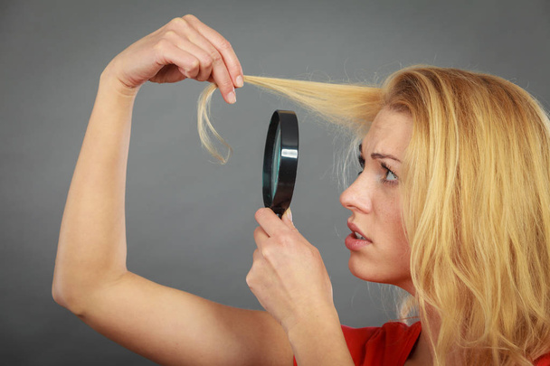 Woman looking at hair through magnifying glass - Foto, immagini