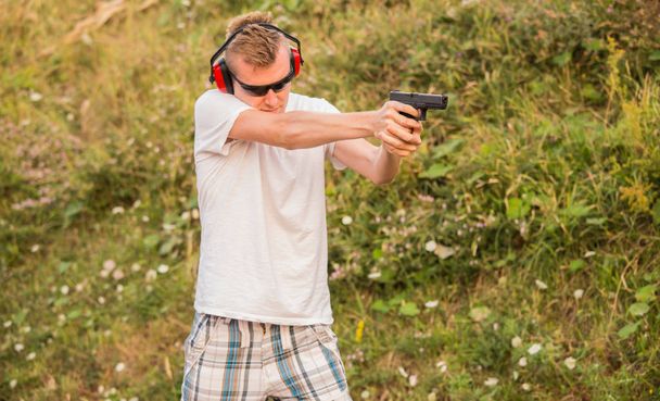 Молодой и сильный кавказский блондин стреляет пулями в врага
 - Фото, изображение