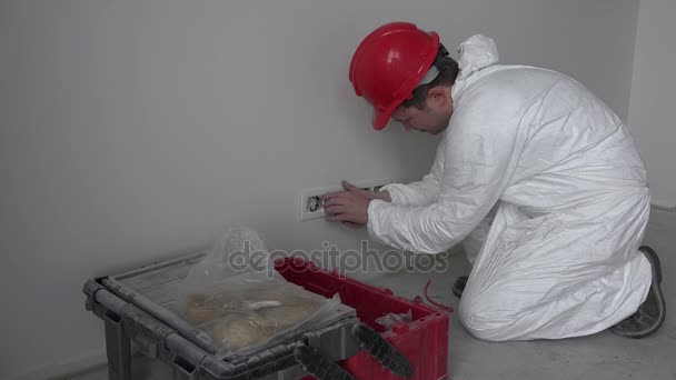 Kavkazská mužské elektrikář montážní zásuvka zásuvky stěnu v nové budově - Záběry, video