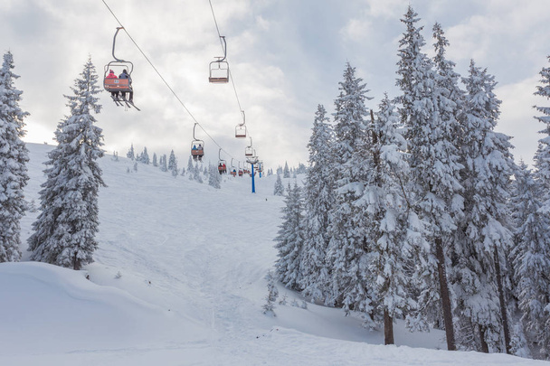 Ski lift with seats going over the mountain and paths from skies - Photo, Image