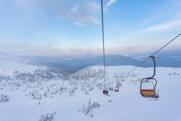 Лыжный подъемник с сиденьями, идущими над горой и тропами с неба
 - Фото, изображение