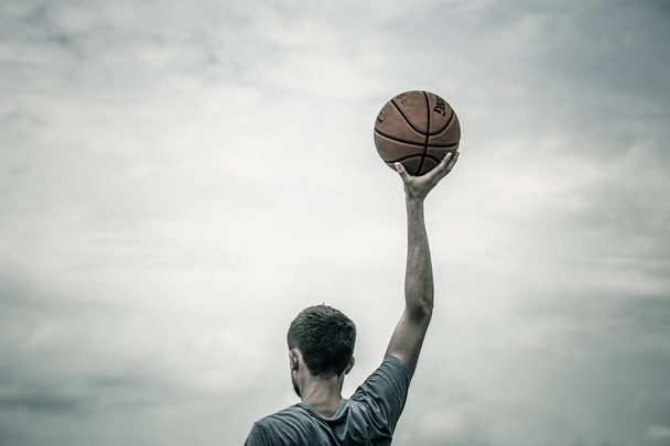 νεαρός άνδρας με μπάλα του μπάσκετ στο δρόμο, τα συναισθήματα του αθλητή - Φωτογραφία, εικόνα