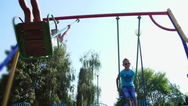 Happy children, a girl and a boy of seven, ride on a swing, on a hot summer day. Slow motion. Cheerful happy childhood, vacation. - Materiaali, video