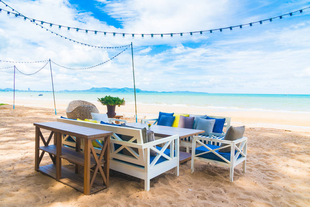 Стул и обеденный стол на пляже и море с голубым небом
 - Фото, изображение