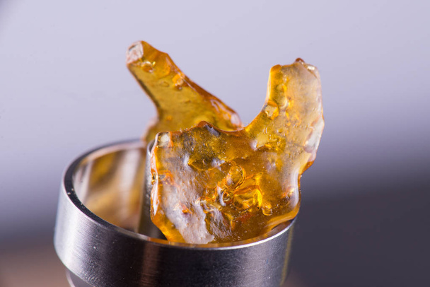 Piece of cannabis oil concentrate aka shatter on a titanium dab  - Photo, Image