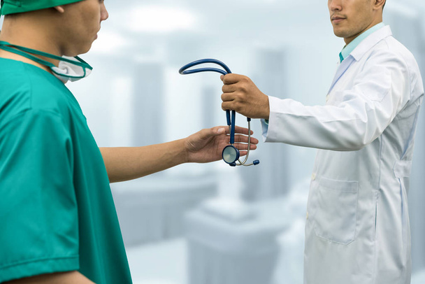 Arzt gibt Stethoskop an Chirurgen (Überweisung) - Foto, Bild