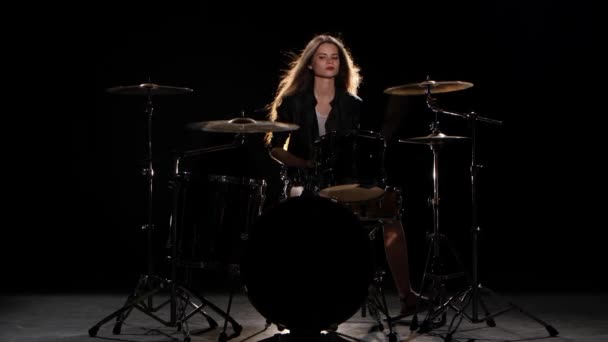 Drummer girl starts playing energetic music, she smiles. Black background - Πλάνα, βίντεο