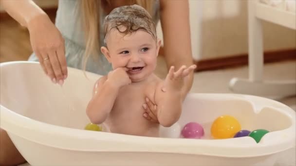 The mother bathes the baby in the bathroom in the room - Video