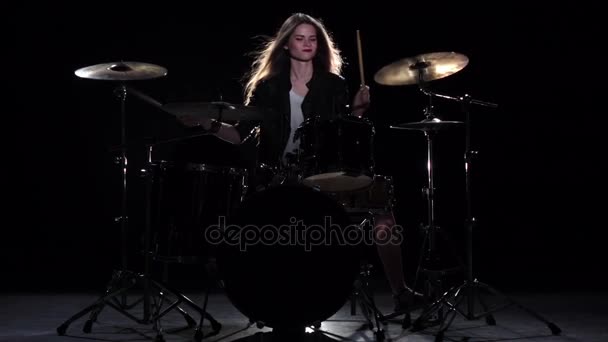 Drummer girl starts playing energetic music, she smiles. Black background. Slow motion - Video