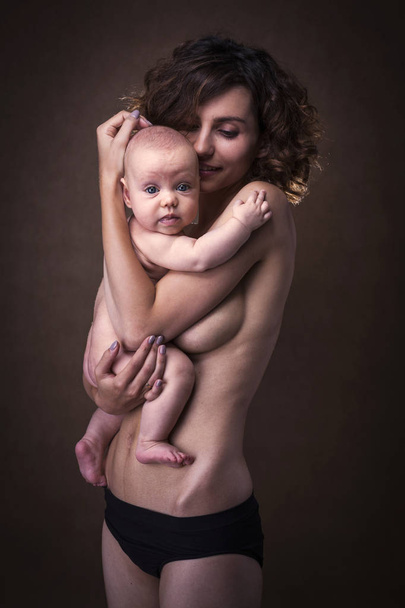 Νεαρή μητέρα κρατώντας ένα μωρό στην αγκαλιά της - Φωτογραφία, εικόνα