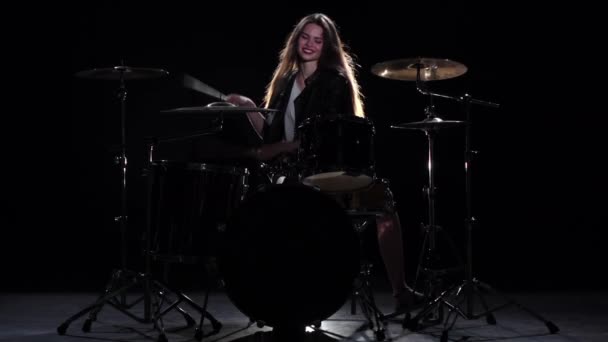 Drummer girl starts playing energetic music, she smiles. Black background. Slow motion - Filmagem, Vídeo