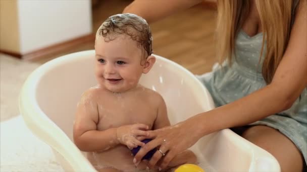 The mother bathes the baby in the bathroom in the room - Záběry, video