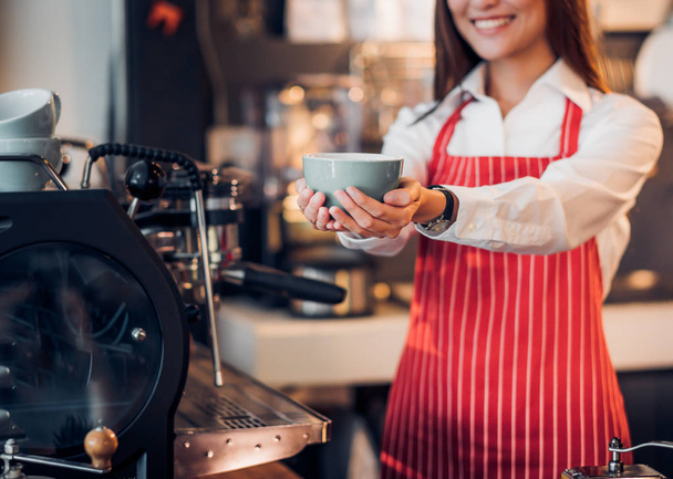 Close up hand of woman barista wear red apron holding hot coffee - Φωτογραφία, εικόνα