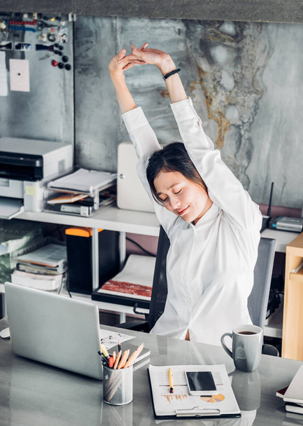 Asian businesswoman raise arm up stretching in front of desk fro - Zdjęcie, obraz