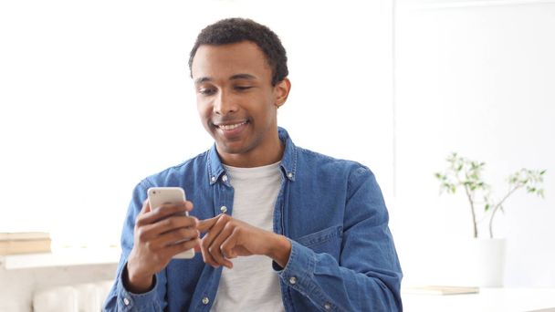 Młody człowiek afro-amerykański, przeglądania stron internetowych na Smartphone - Zdjęcie, obraz