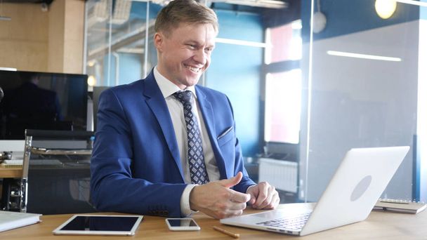 Усміхнений бізнесмен розслабляється онлайн відео чат в офісі
 - Фото, зображення
