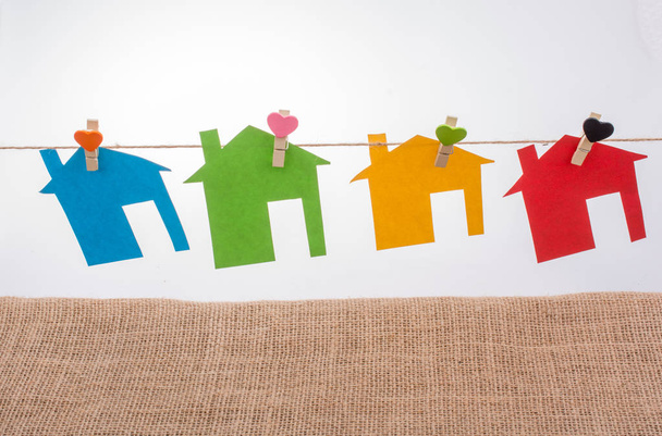 Маленькие домики из цветной бумаги, прикрепленные к веревке с зажимом для сердца - Фото, изображение