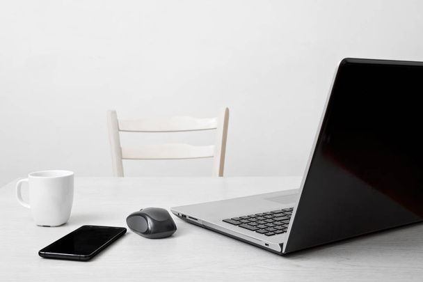Schone werkplek met laptop, telefoon, koffie cup en computer muis - Foto, afbeelding