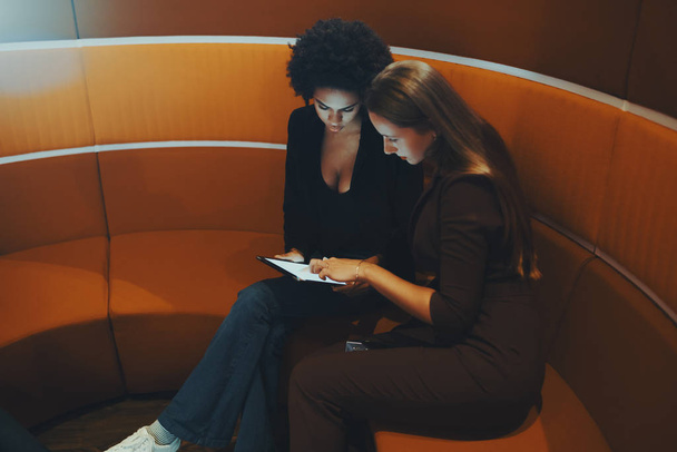 Oranje gebogen zitbank met twee zakenvrouw op het - Foto, afbeelding