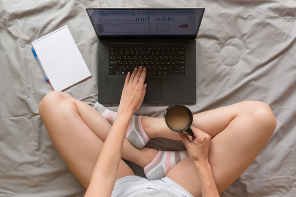 Концепция домашнего офиса: девушка, работающая с ноутбуком в постели дома
 - Фото, изображение