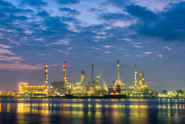 Завод по переработке нефти и судоходная погрузочная платформа на сумерках
 - Фото, изображение