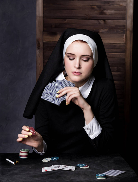 beautiful catholic nun playing cards. Rotten religion - Photo, Image