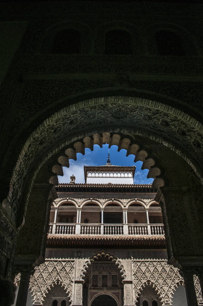 Spanien: der Patio de las doncellas, der Hof der Jungfrauen, das Zentrum des öffentlichen Bereichs des Königs-Peter-i-Palastes, von einem Hufeisenbogen im königlichen Alcazar von Sevilla aus gesehen - Foto, Bild