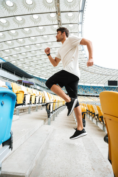 Side view of a sporty athlete man running upstairs - Valokuva, kuva