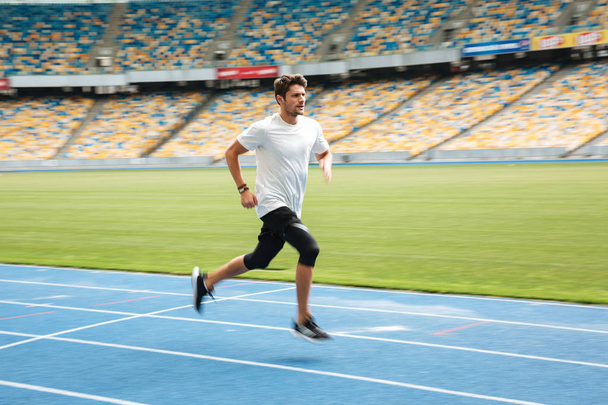 Side view of a young professional sprinter running - Foto, imagen