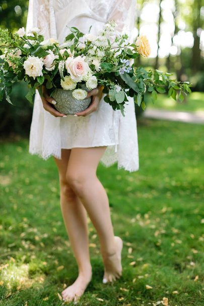 beauty, appearance, nature concept. charming sylphelike creature with long thin legs wearing white dress with lace cloak holding vase with large gorgeous bouquet of flowers - Foto, Imagen