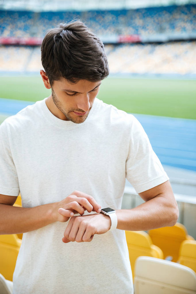 Concentrated young sports man looking at watch - Foto, Bild