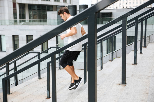 Side view of a sporty athlete man running downstairs - Foto, Imagem