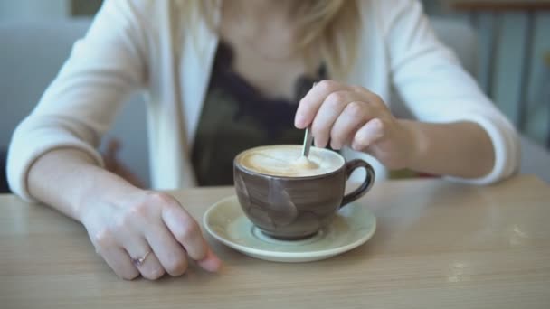 las manos de las niñas agitar el azúcar en una taza de café con leche de cerca
 - Imágenes, Vídeo