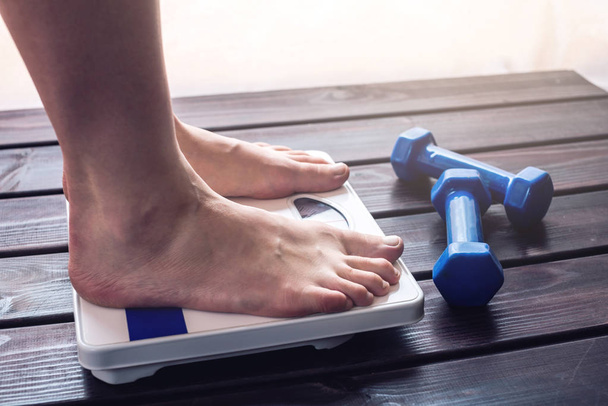 Kadın ayakları mekanik ölçekler üzerinde halter ayakta. Spor eğitim, zayıflama ve kilo kaybı kavramı - Fotoğraf, Görsel