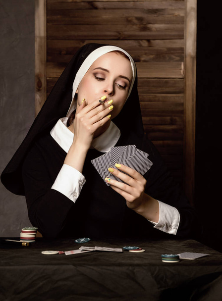 beautiful catholic nun smokes and playing cards. Rotten religion - Foto, Imagem