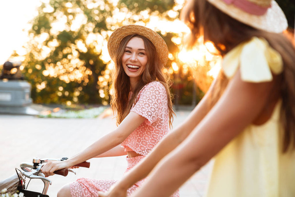Two pretty smiling girls on a bicycle ride - Zdjęcie, obraz