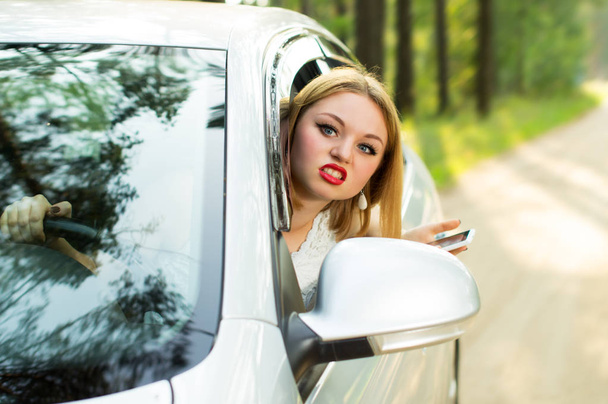Beautiful girl looks out the car window and strongly swears - Photo, Image