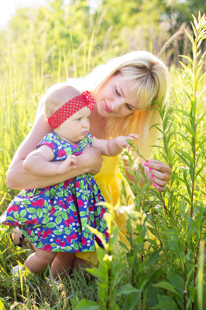 Happy mother with daughter, consider the flowers outdoors - Фото, зображення
