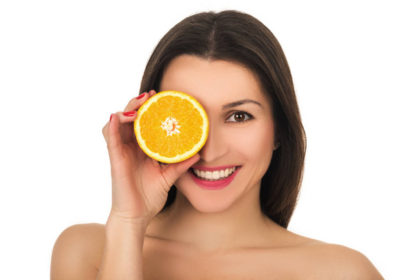 Portrait on young smiling woman with half of orange near face - Zdjęcie, obraz