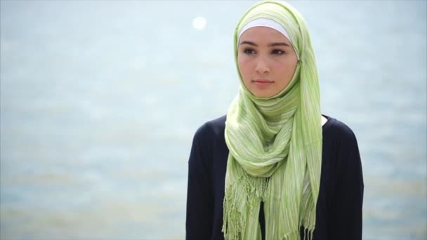 海の近くに立って、思慮深く見て、イスラム教徒の女性の肖像画 - 映像、動画