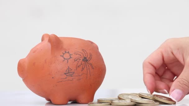 Woman saving money into a traditional clay piggy bank for holidays - Footage, Video