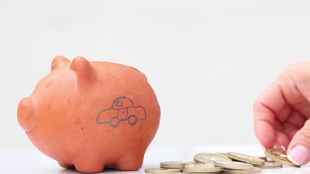 Frau spart Geld in ein traditionelles Sparschwein aus Ton für ein Auto - Filmmaterial, Video