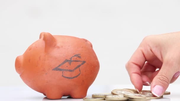 Woman saving money into a traditional clay piggy bank to study - Footage, Video