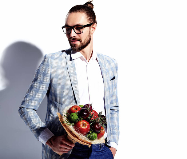 portrait of handsome fashion stylish hipster businessman model man dressed in elegant light blue suit in glasses isolated on white with fresh bouquet of creative flowers - 写真・画像