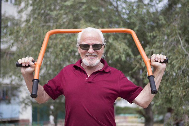 Старший чоловік тренує спортивне обладнання на відкритому повітрі
 - Фото, зображення