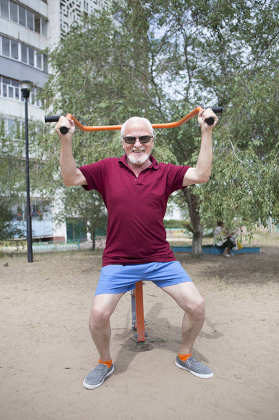 Старший мужчина тренируется на спортивном оборудовании на открытом воздухе
 - Фото, изображение
