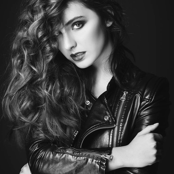 Beautiful young woman posing in black leather jacket over grey b - Photo, Image